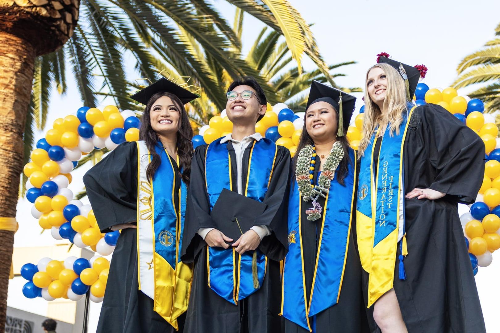 A group of San José State University graduates pose for a photo dressed in their graduation cap and gown. 